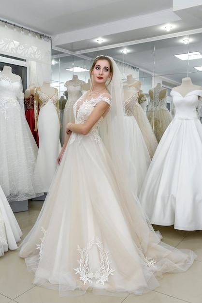 Elegante signora allegra in abito da sposa in piedi nel salone di nozze