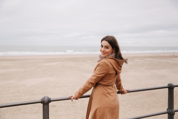 Elegante signora con trucco in un bel cappotto in piedi lungo il Mare del Nord Donna sorriso