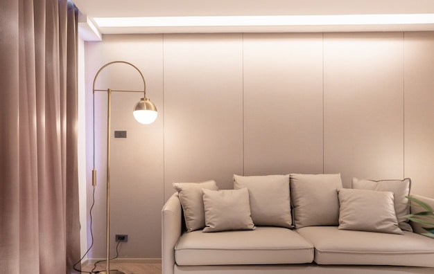 Elegante soggiorno di lusso con divano in pelle beige, lampada da parete in acciaio dorato