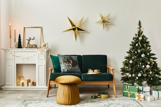 Elegante soggiorno natalizio con divano verde, camino bianco, albero di Natale e ghirlanda, stelle, regali e decorazioni. Tempo per la famiglia. Modello.