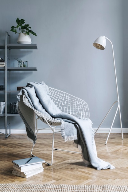 Elegante soggiorno nordico con poltrona di design, tavolino da caffè, lampada bianca, leggio, mobili, moquette, piante e accessori eleganti in un moderno arredamento per la casa