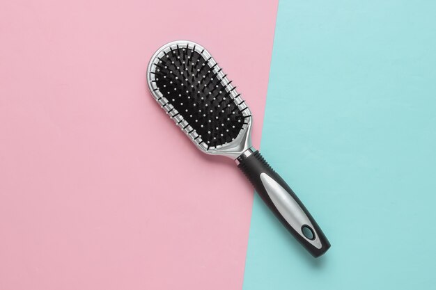 Elegante spazzola per capelli su sfondo rosa pastello blu