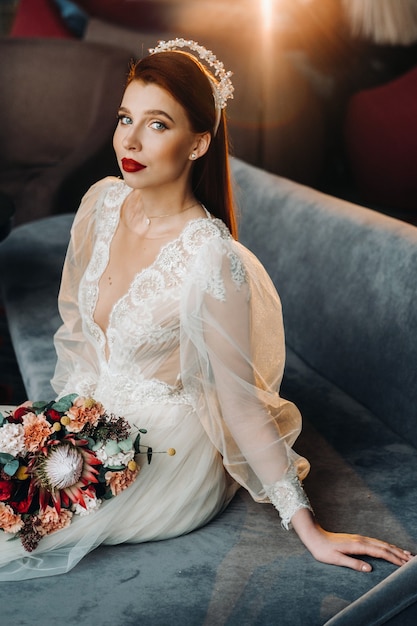 Elegante sposa dai capelli rossi in un abito con maniche e un bouquet all'interno