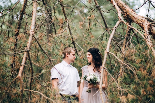 Elegante sposa e sposo che propongono insieme all'aperto in un giorno di nozze