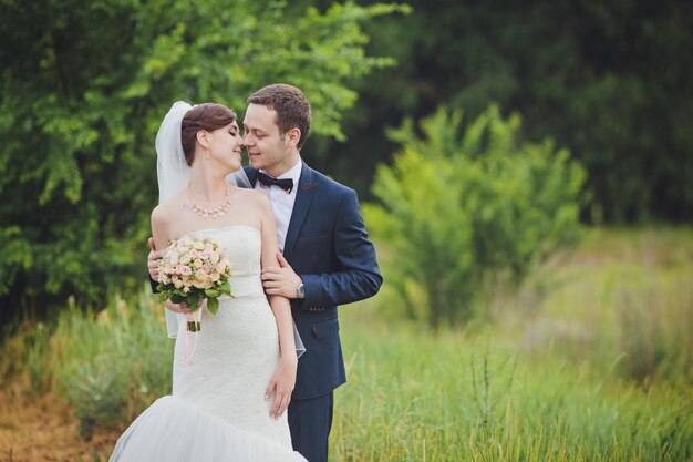 Elegante sposa e sposo che propongono insieme all'aperto