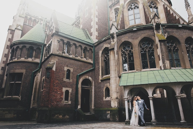 Elegante sposa e sposo che si abbracciano sullo sfondo della vecchia chiesa in strada soleggiata Momento romantico