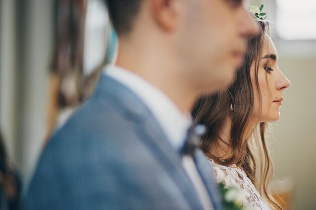 Elegante sposa e sposo in piedi durante il santo matrimonio in chiesa Cerimonia di nozze in cattedrale Coppia di nozze spirituali classiche con candele moderne accese