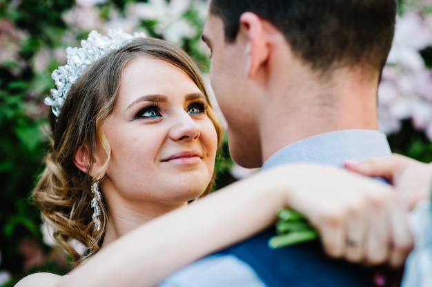 Elegante sposa felice con corona e sposo. Bellissimi occhi felici, bellissimo trucco.