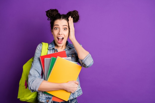 Elegante studente con capelli ricci in posa contro il muro viola