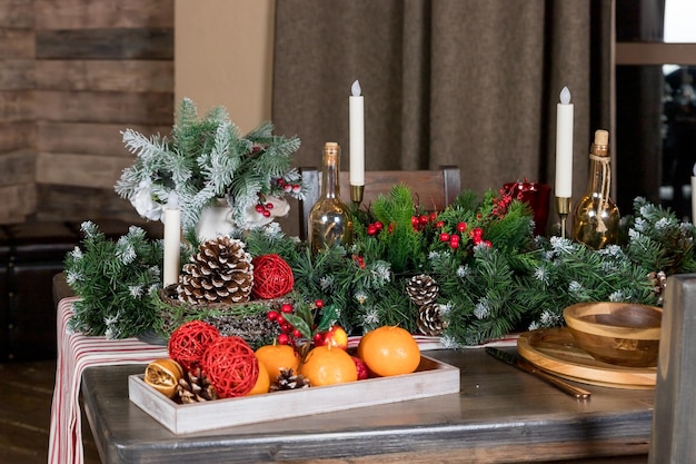 Elegante tavola da pranzo di Natale Decorazione di candele da tavola di Natale rami di ginepro e tovaglioli piatti di legno Decorazioni di Capodanno in soggiorno in stile country