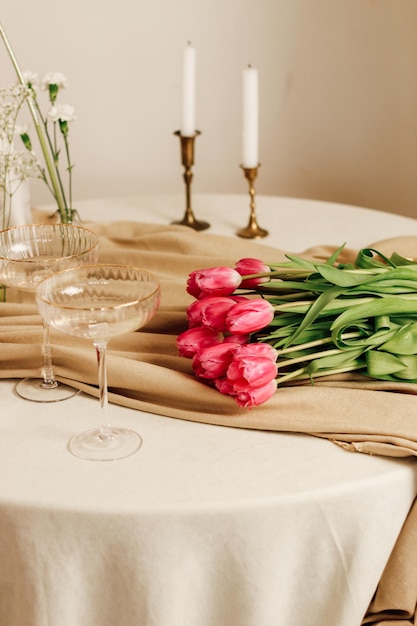 Elegante tavola romantica all'interno con bicchieri e un bouquet di tulipani