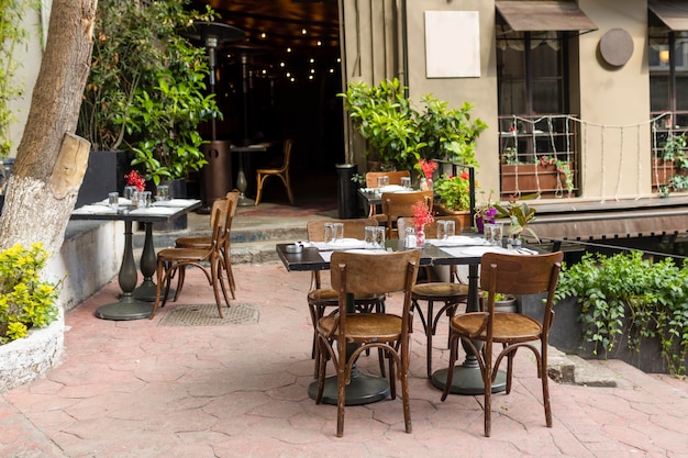 Elegante tavolo in legno e sedie vuote vicino al caffè sullo sfondo della finestra e del muro della città vecchia