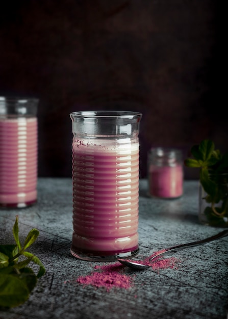 Elegante tè rosa matcha in un bicchiere trasparente con un cucchiaio su un tavolo di marmo scuro e uno sfondo nero