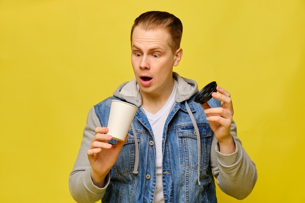 Elegante uomo caucasico detiene una tazza di carta usa e getta per caffè aperto