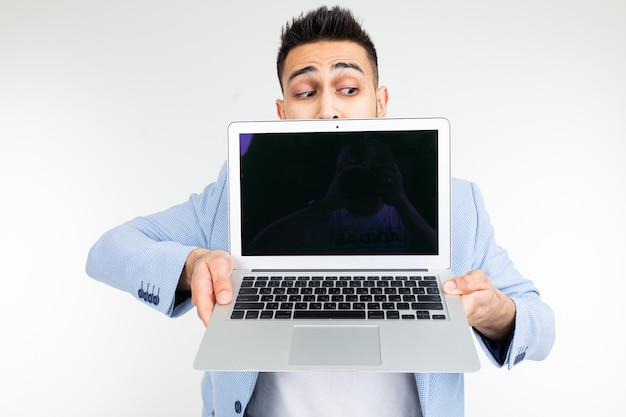 Elegante uomo di successo in una giacca dimostra uno schermo portatile con spazio per la pubblicità su uno sfondo bianco studio