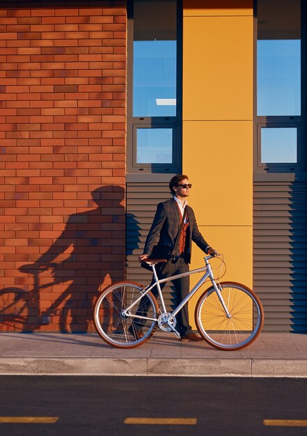 Elegante uomo esecutivo con la bicicletta nel centro della città