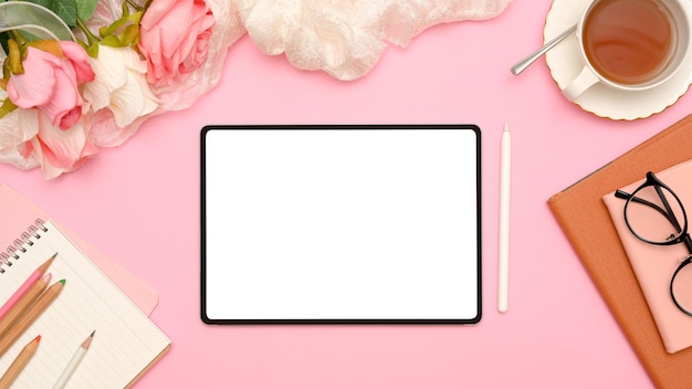 Elegante vista dall'alto dell'area di lavoro dell'ufficio femminile rosa con mockup e accessori per lo schermo bianco del tablet