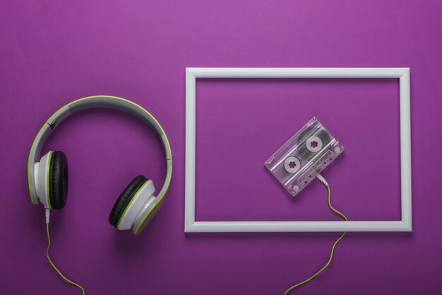 Eleganti cuffie stereo cablate con audiocassetta su superficie viola con cornice bianca