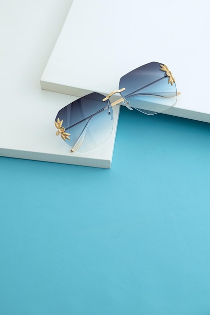Eleganti occhiali da sole blu su sfondo bianco e blu Tavolo blu