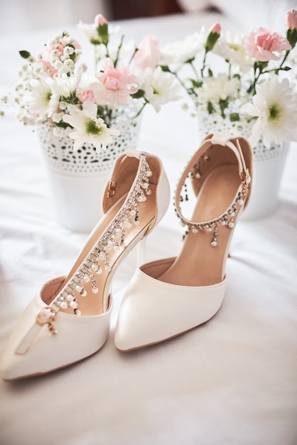 Eleganti scarpe da sposa bianche, profumo, fiori e gioielli.