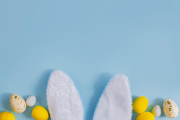 Eleganti uova di Pasqua e orecchie da coniglio piatte su sfondo blu con spazio per la copia Modello di biglietto di auguri di buona Pasqua Banner di vacanza moderna Composizione minima di caccia di Pasqua