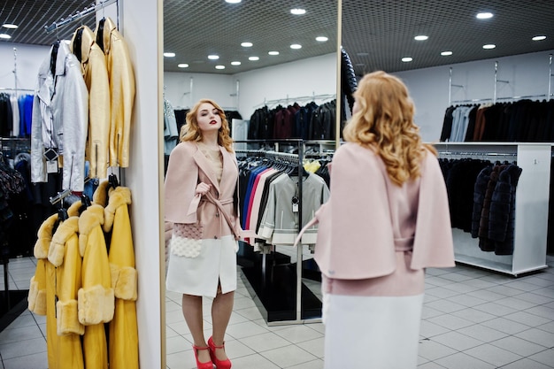 Eleganza ragazza bionda in cappotto al negozio di pellicce e giacche di pelle