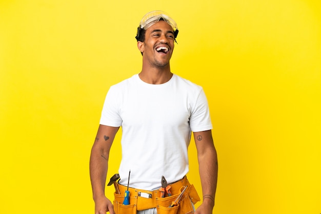 Elettricista afroamericano sopra il muro giallo isolato che ride