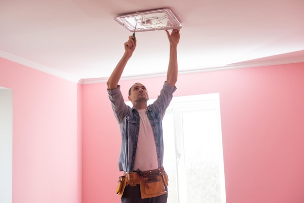Elettricista che controlla l'illuminazione al soffitto della casa, concetto tecnico