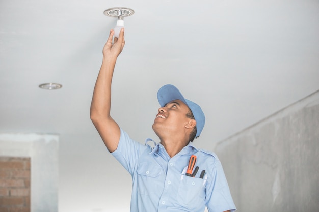 Elettricista che installa lampadina nel downlight