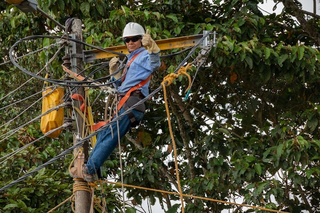 Elettricista maschio che lavora all'altezza di un palo della luce Elettricista