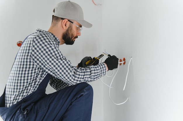 Elettricista professionista che lavora su un impianto elettrico domestico sta installando una presa a muro