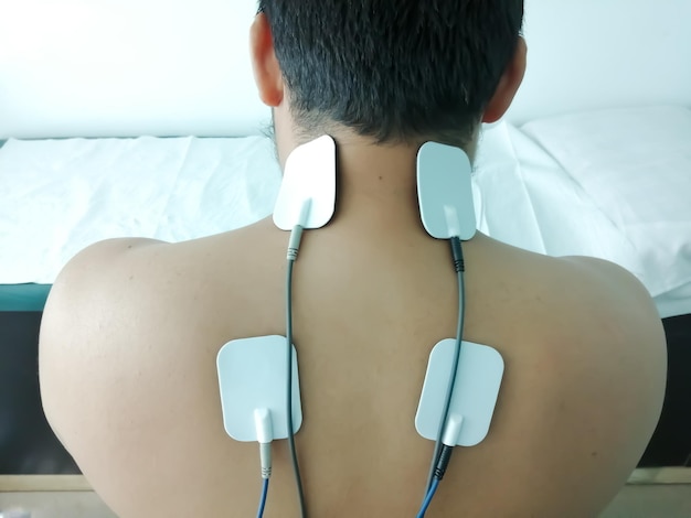 Elettrostimolazione in fisioterapia. Un uomo con un mal di schiena alla spalla posteriore.