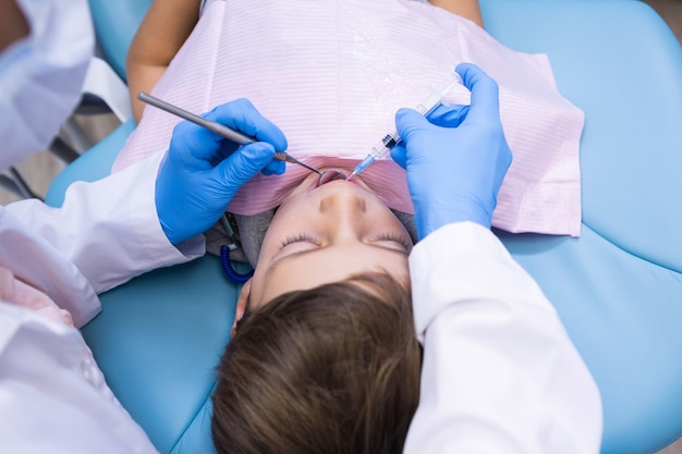 Elevato angolo di visione del dentista in possesso di apparecchiature mediche durante l'esame del ragazzo