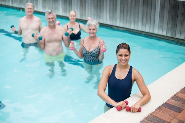 Elevato angolo di visione del trainer femminile con nuotatori senior in piedi in piscina