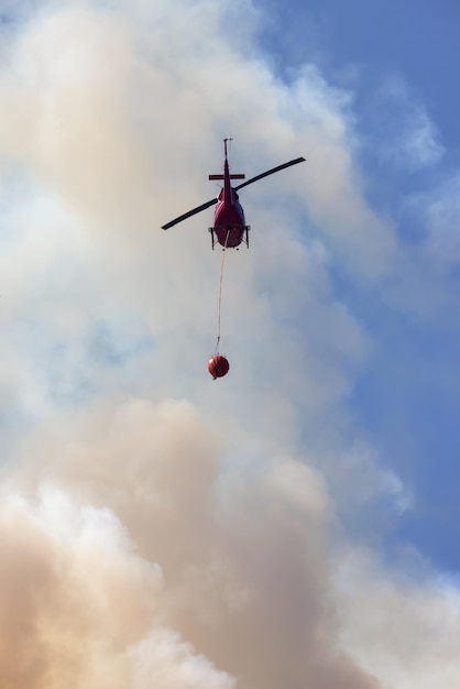 Elicottero di servizio Wildfire che sorvola BC Forest Fire e Smoke sulla montagna vicino a Hope