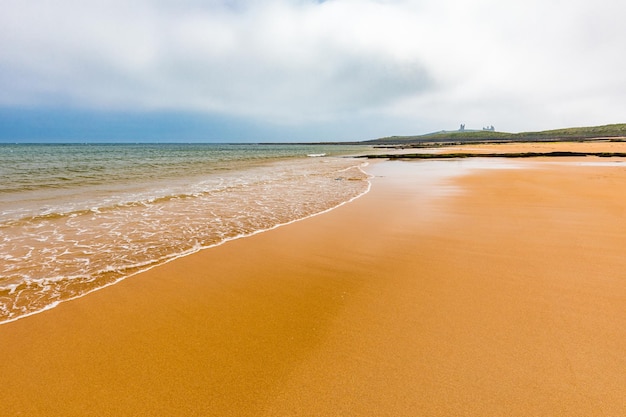 Embleton Bay e Burn spiaggia sabbiosa con le rovine del castello di Dunstanburgh