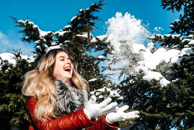 Emotiva ragazza dagli occhi azzurri che soffia neve nelle sue mani. Gelido inverno.