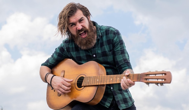 Emotivo bell'uomo cantante e chitarrista chitarrista acustico musicista maturo hipster con barba brutale ragazzo caucasico che suona la chitarra musica country uomo barbuto che canta una canzone