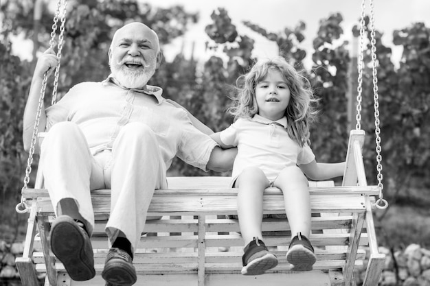 Emozionati nipoti stupiti e vecchio nonno che oscillano nel giardino di primavera nonno e nipote h