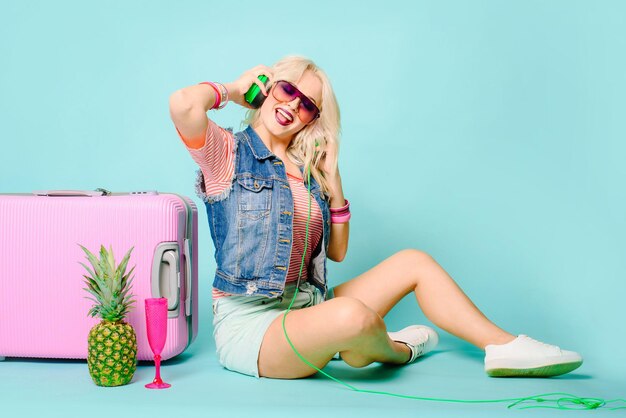 Emozione positiva donna con borsa rosa valigia su sfondo colorato. Concetto di viaggio.