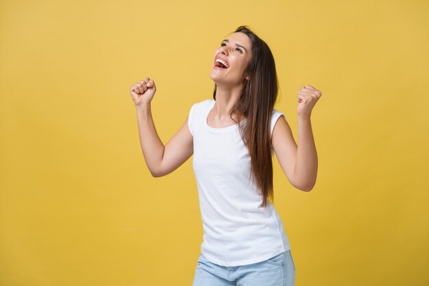 Emozioni, espressioni, successo e concetto di persone - felice giovane donna o adolescente che celebra la vittoria isolata su sfondo giallo.