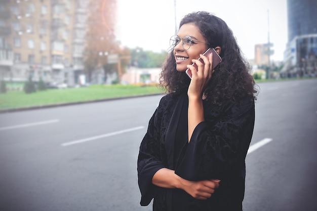 Emozioni positive. Concetto di stile di vita. Primo piano di una giovane donna di razza mista usa un telefono.