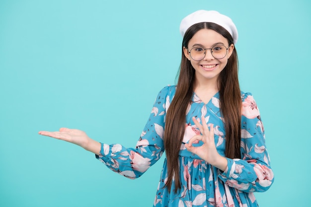 Emozioni positive e sorridenti dell'adolescente felice Ritratto ravvicinato della ragazza del bambino dell'adolescente che mostra nello spazio della copia che punta alla pubblicità degli annunci isolata su sfondo bianco