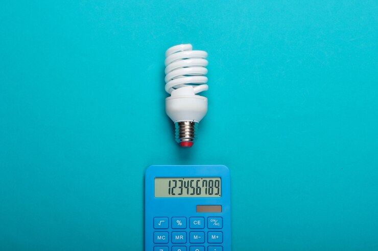 Energy saving. Calculator with spiral light bulb on blue background. Top view