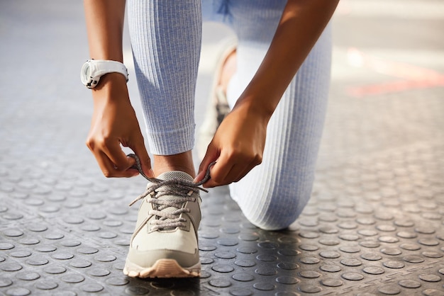 Entra nel cerchio dei vincitori Inquadratura di una donna irriconoscibile che si allaccia i lacci delle scarpe prima di un allenamento in palestra