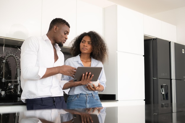 Entrambe le giovani coppie discutono di affari in cucina a casa usando computer portatili