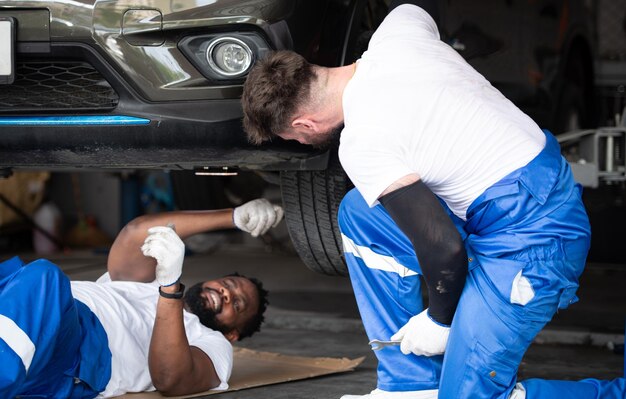 Entrambi i meccanici di auto che lavorano in un negozio di riparazione automobilistica controllano il funzionamento del motore