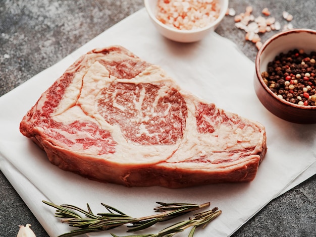 Entrecote crudo su carta bianca Preparazione della bistecca di manzo cruda per la griglia del barbecue