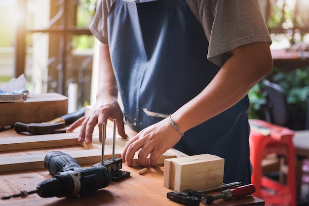 Entrepreneur Woodwork misura le assi per assemblare le parti e costruire un tavolo di legno per il cliente
