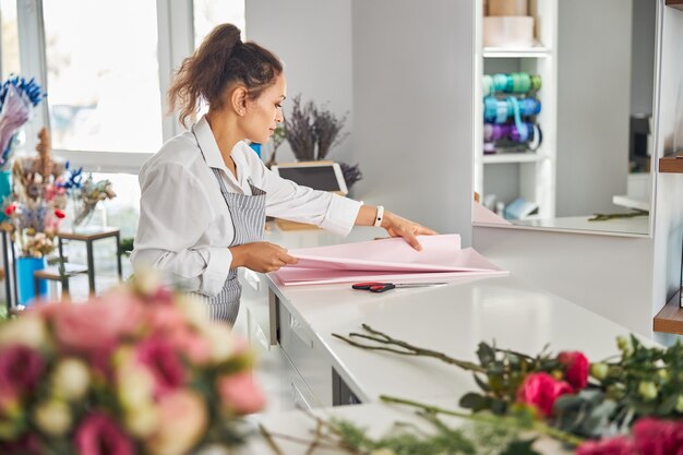 Entusiasta donna bruna che tocca la carta da regalo sul tavolo